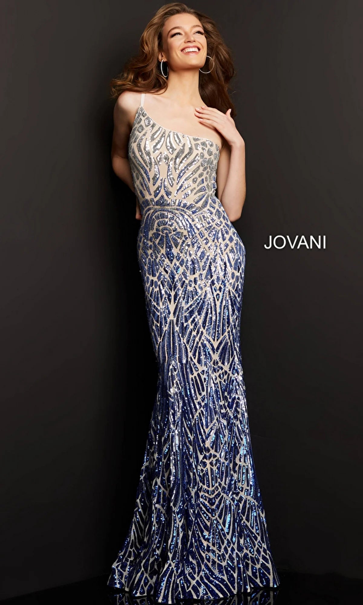 A woman poses confidently in a sparkling blue and silver gown, smiling charmingly. The background is dark, highlighting the elegance of the dress. JOVANI is displayed near the bottom.