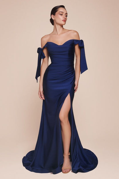 A figure in a sleek, off-the-shoulder navy gown with ribbon sleeves stands confidently. The dress features a thigh-high slit, accentuating elegance against a soft, neutral background.