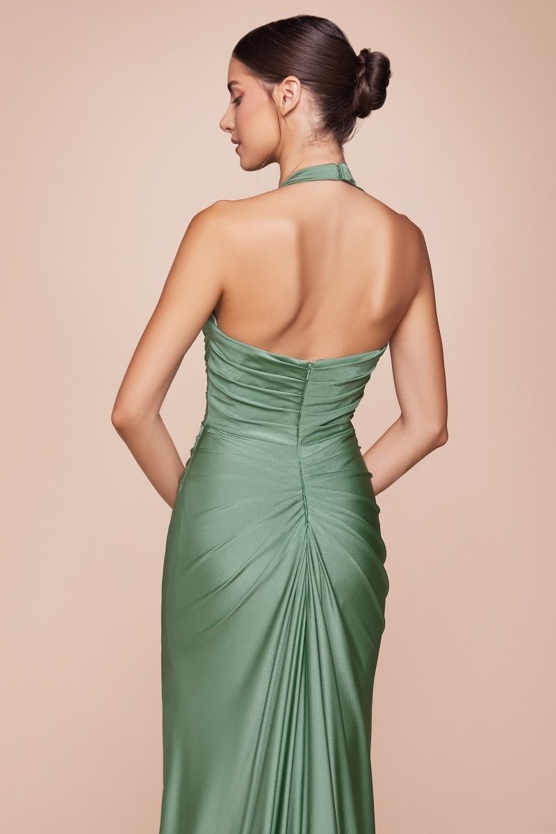 A woman is seen from behind, wearing a fitted, elegant green dress that features gathered fabric and a halter neck. The background is a soft, neutral tone.