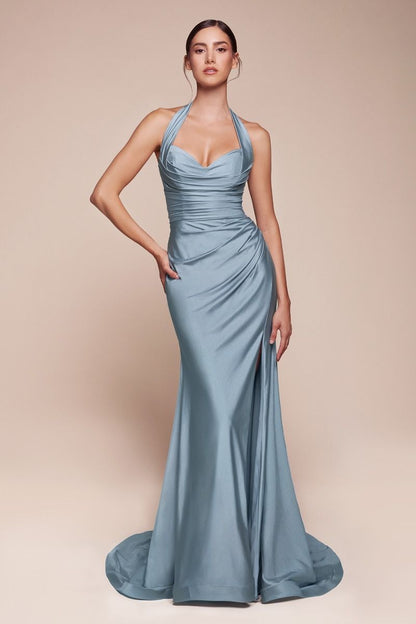 A person stands confidently, wearing a form-fitting, light blue gown with a halter neckline and flowing train. The background is a soft beige, emphasizing the elegance of the outfit.