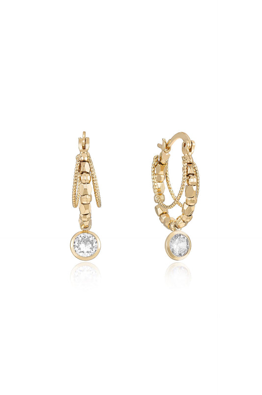 Gold hoop earrings dangle, featuring intricate designs and sparkling circular gemstones. They reflect light against a neutral background, emphasizing their elegance and detailed craftsmanship.