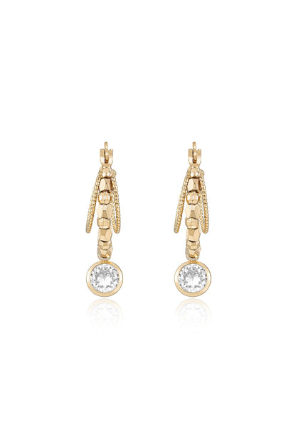 Gold earrings are displayed, featuring a textured design with a round, sparkling stone at the bottom. The setting is reflective, enhancing their elegant appearance.