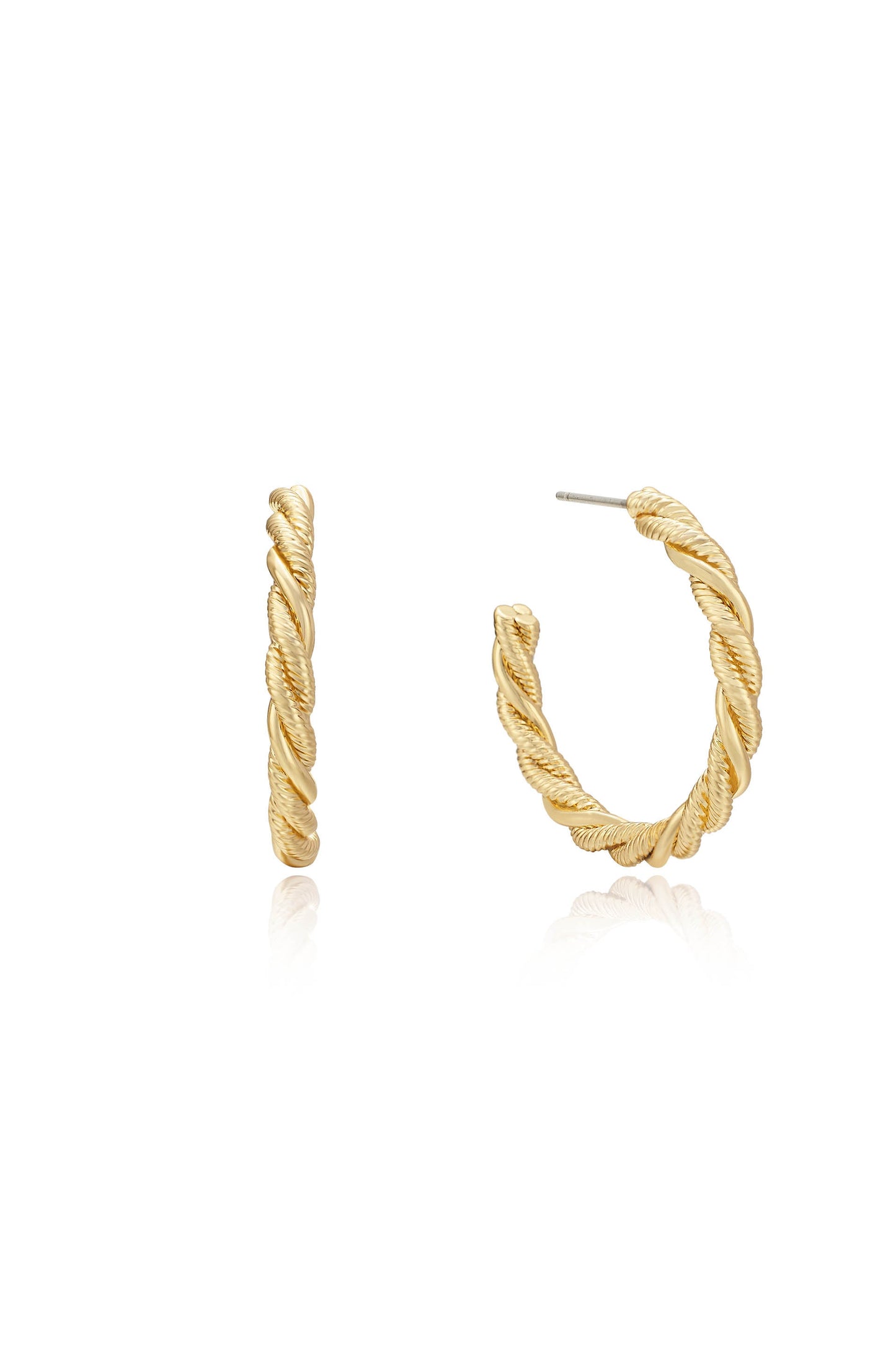 A pair of twisted gold hoop earrings rests on a reflective surface, showcasing their intricate design and polished finish in a neutral setting.