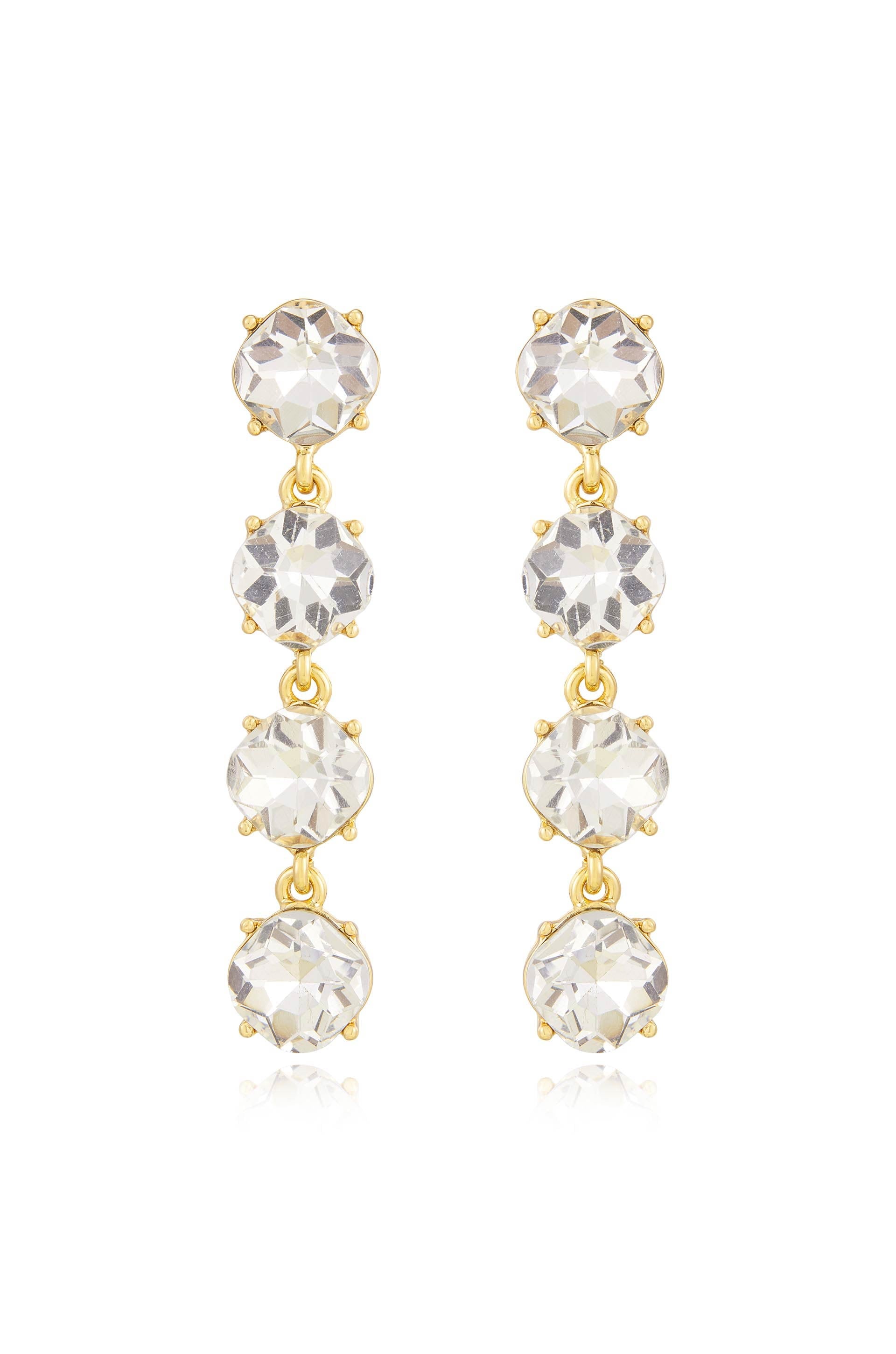 Two elegant golden drop earrings with three sparkling clear crystals each hang vertically. They are designed to add sophistication and shine, suitable for formal or festive occasions.