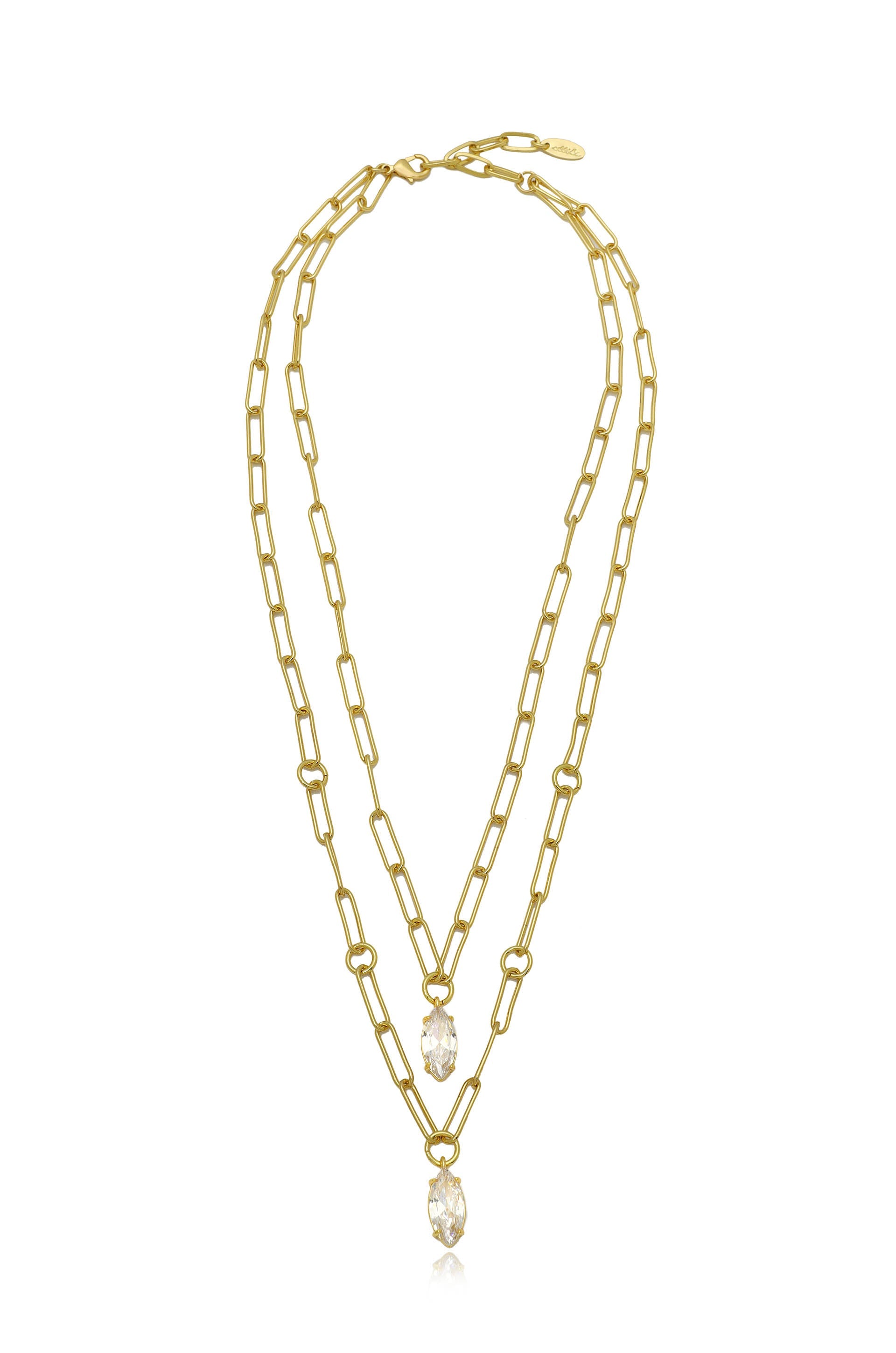 A gold layered necklace features elongated links and two sparkling crystal pendants hanging from the center, set against a plain white background. The design is elegant and modern.