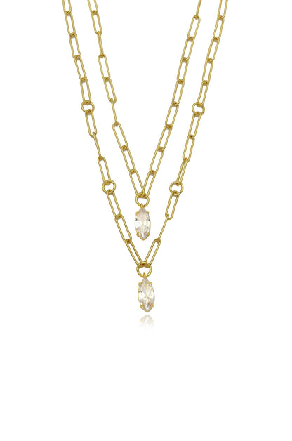 A layered gold chain necklace features elongated links and two clear pendants hanging at different lengths, set against a plain white background. The overall look is elegant and modern.