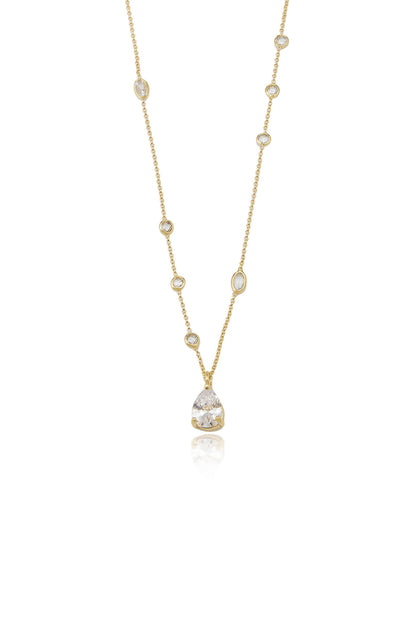 A delicate gold necklace features a central pear-shaped gemstone pendant, with smaller round and oval stones evenly spaced along a fine chain. The background is minimal and white.