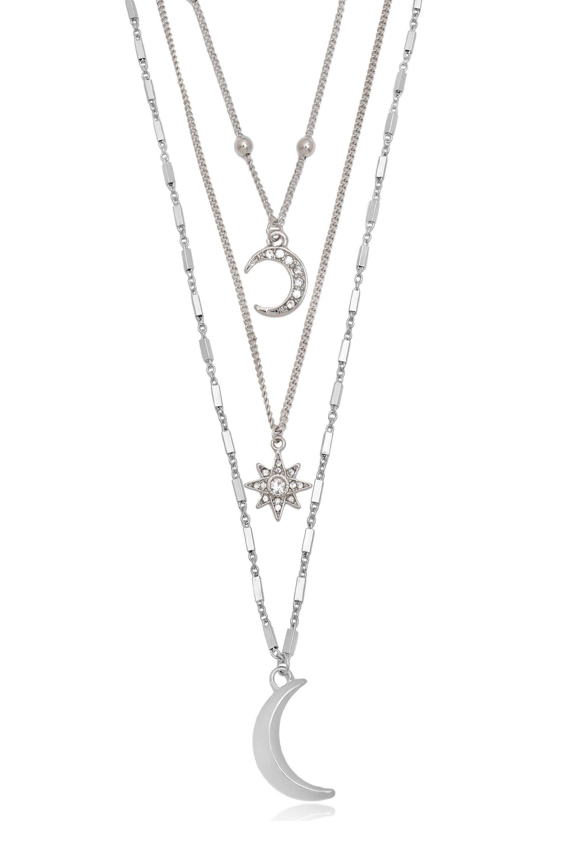 Three layered silver necklaces showcase intricate pendants: a small decorated crescent moon, a larger integrated crescent moon, and a sparkling star. The chains vary in design and thickness.