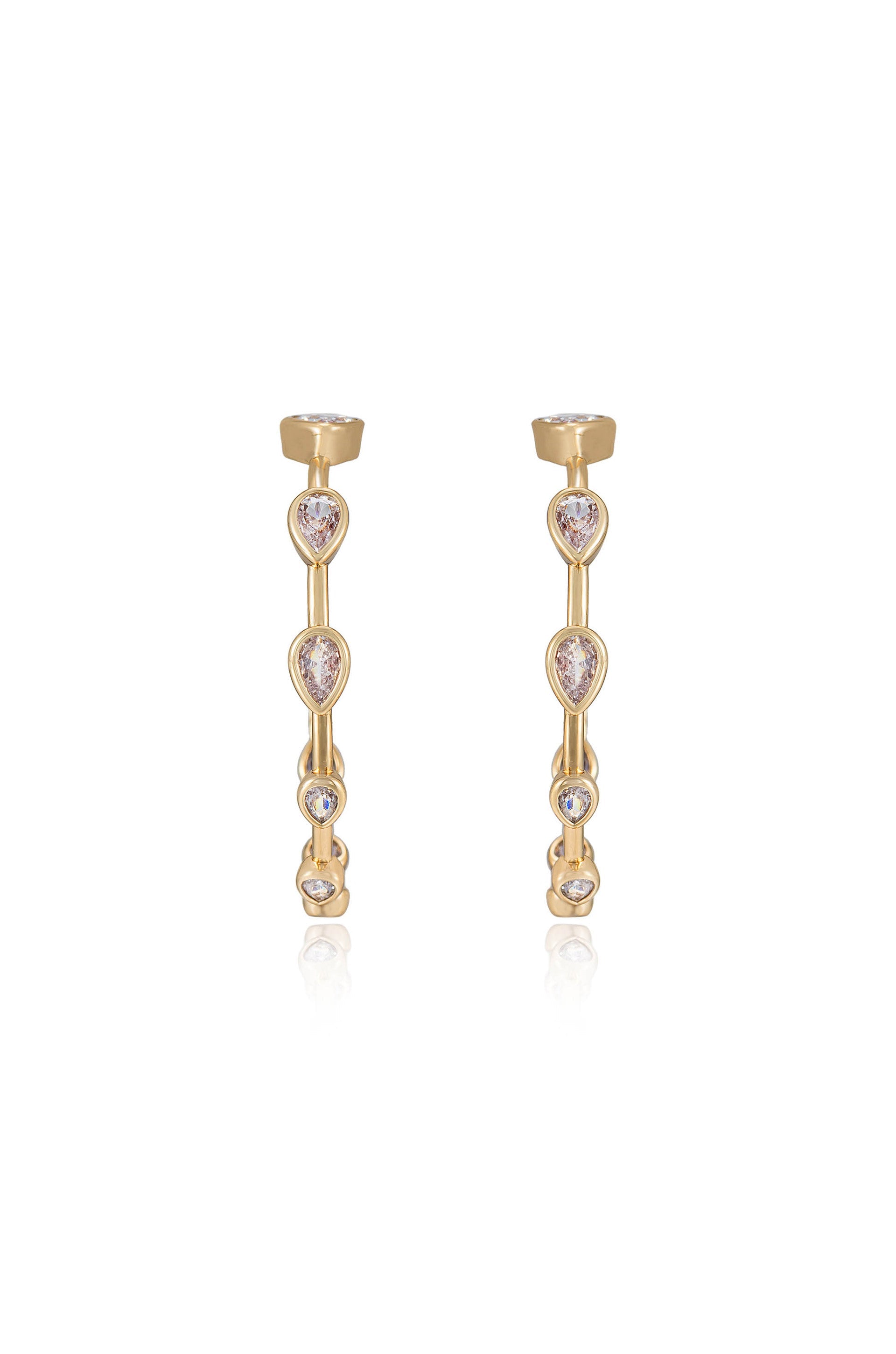 Two gold earrings feature a linear design adorned with teardrop and round stones. They are positioned upright against a reflective surface, showcasing their elegance and shine.