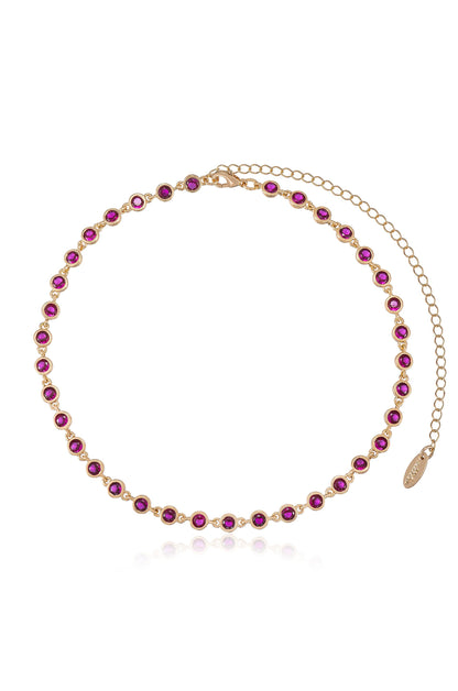 A delicate gold necklace features a series of round, deep pink gemstones set in a uniform pattern. It includes a clasp with an adjustable chain for sizing.