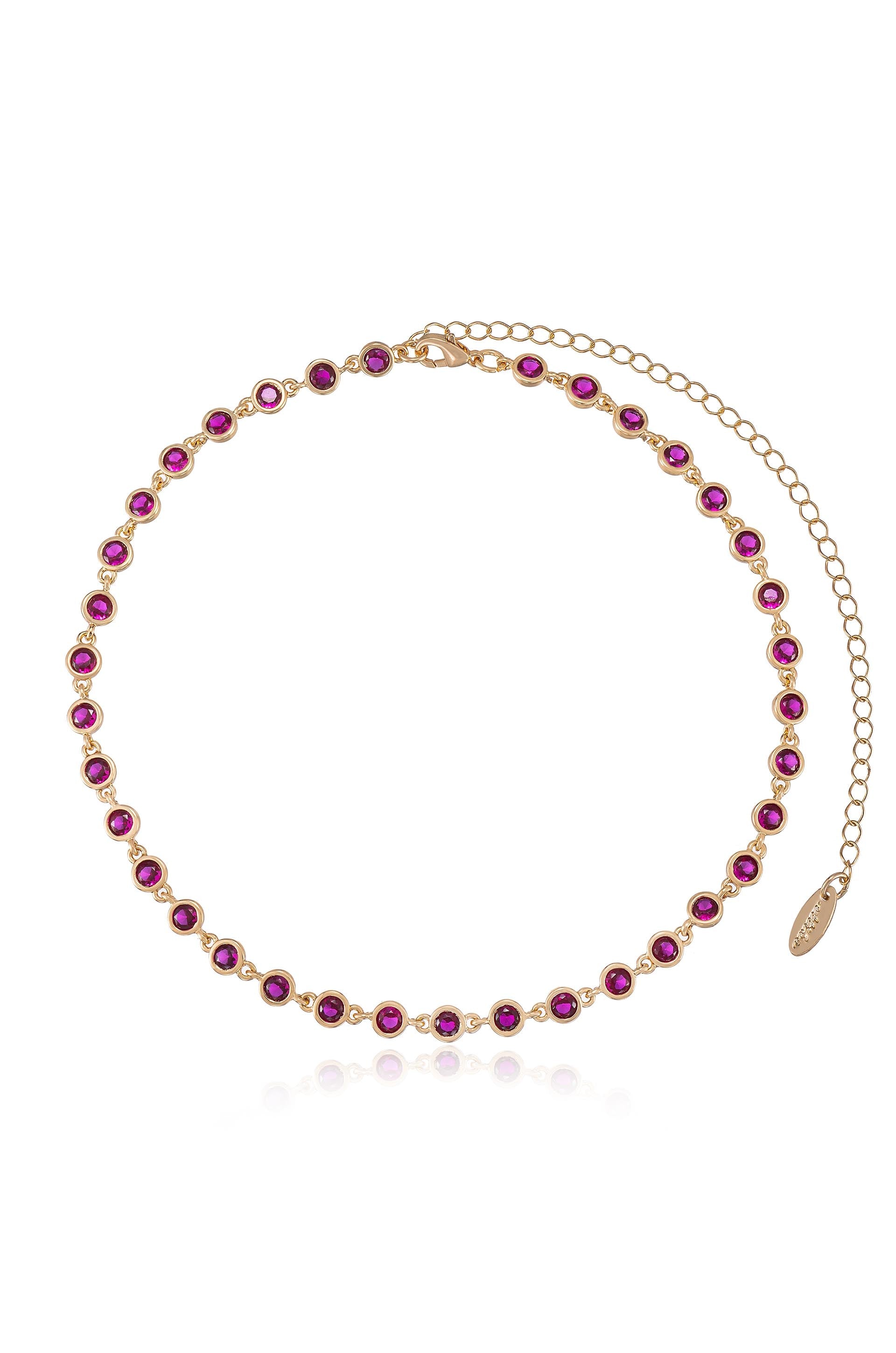 A gold chain necklace features multiple round, purple gemstones evenly spaced along its length, with an adjustable clasp and a short chain extension for sizing flexibility.