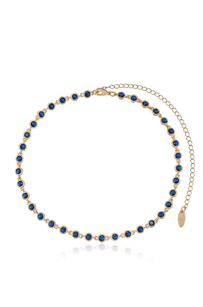 A delicate gold chain necklace features evenly spaced blue gemstones. The necklace is designed for wearing around the neck, showcased against a light background.