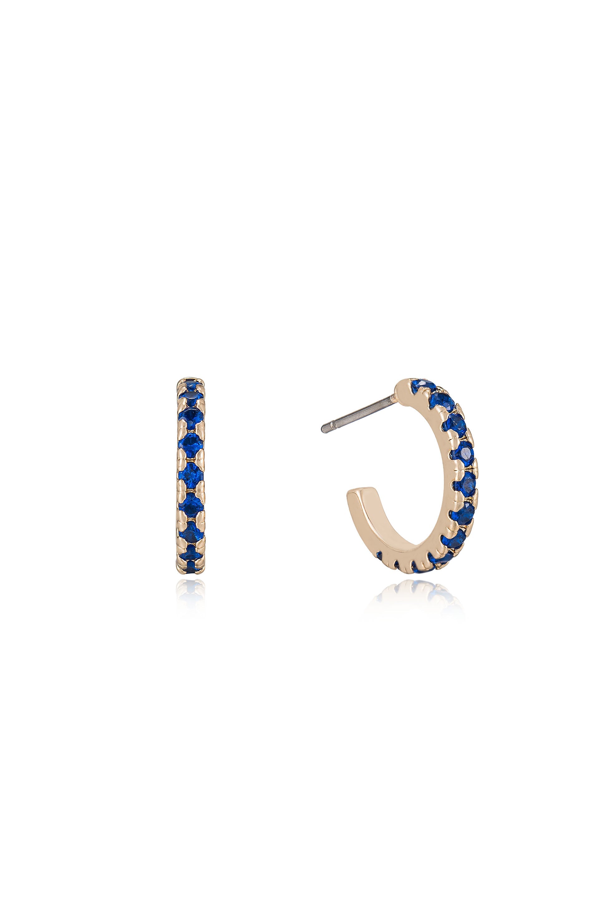 Gold hoop earrings adorned with blue gemstones are displayed, showcasing a shiny surface. The earrings rest on a reflective surface against a plain white background, emphasizing their design.