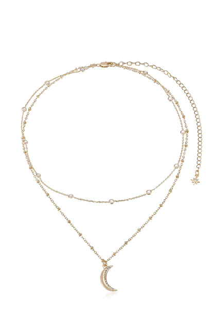 A layered gold necklace features sparkling beads and a crescent moon pendant adorned with rhinestones, displayed against a white background, emphasizing its delicate design and elegance.