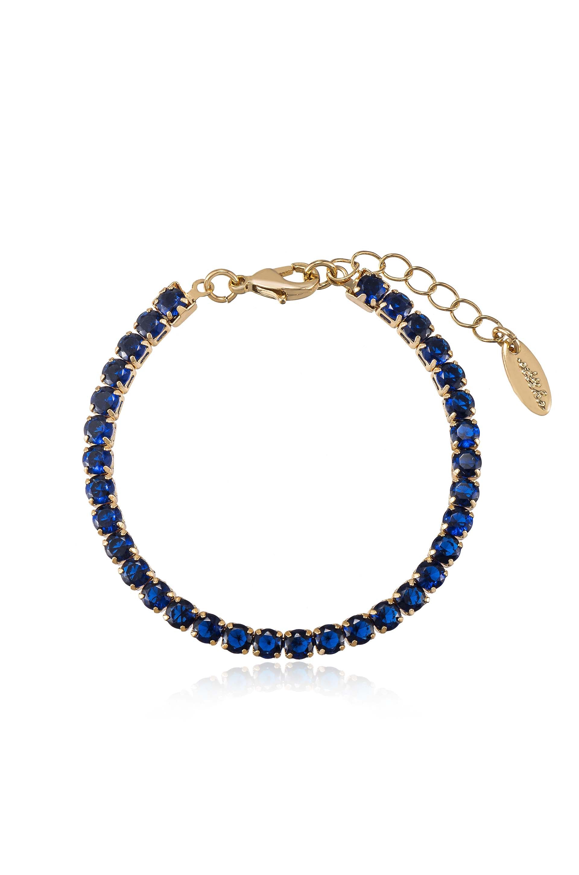 A gold bracelet decorated with alternating blue gemstones seamlessly links together, showcasing a delicate chain extension and clasp for adjustable wearing. It rests against a white background, enhancing its elegance.