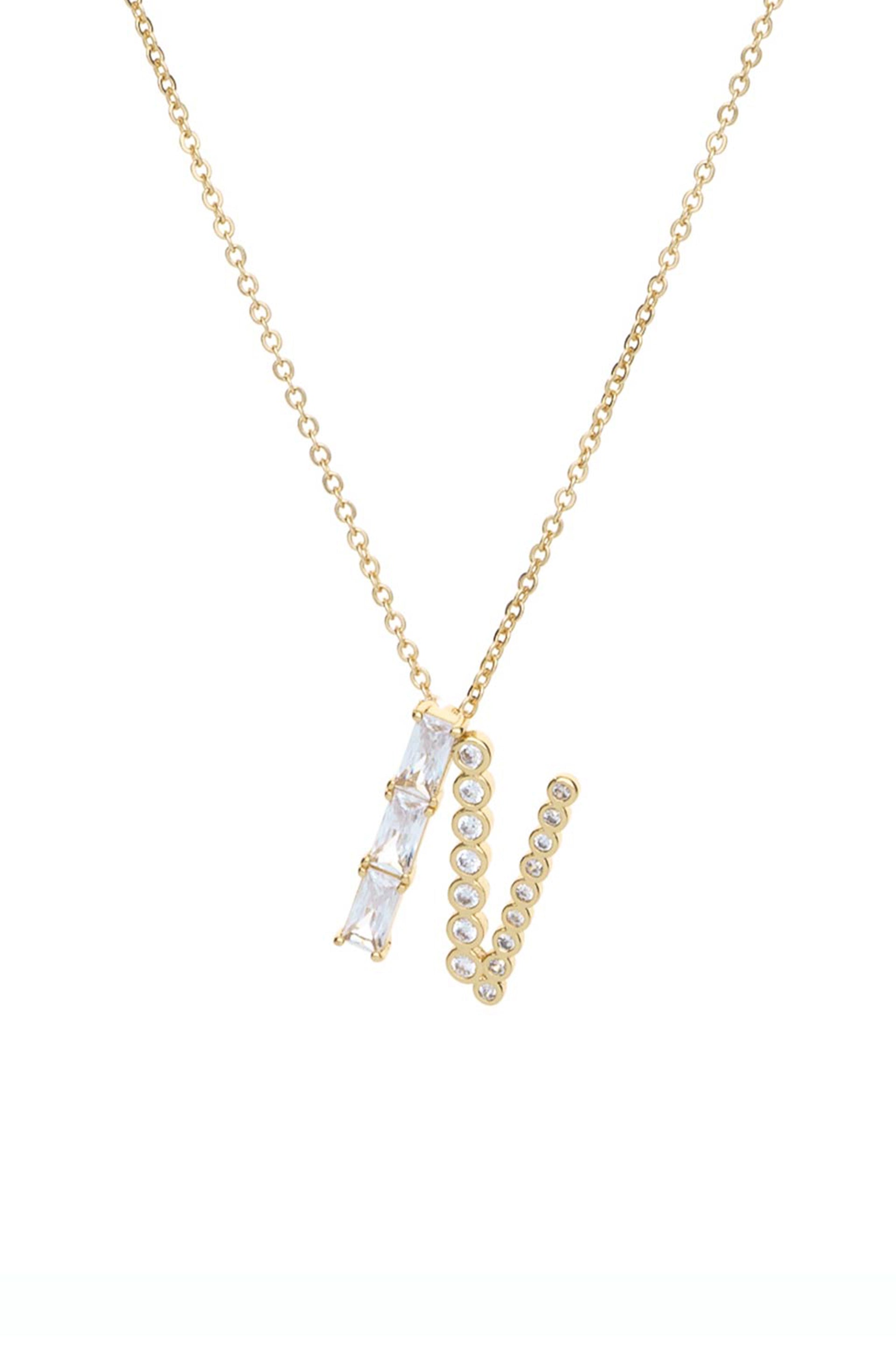 A gold necklace features two distinct pendant styles: one with three clear stones arranged vertically and another with a line of small, round clear stones, both set against a white background.