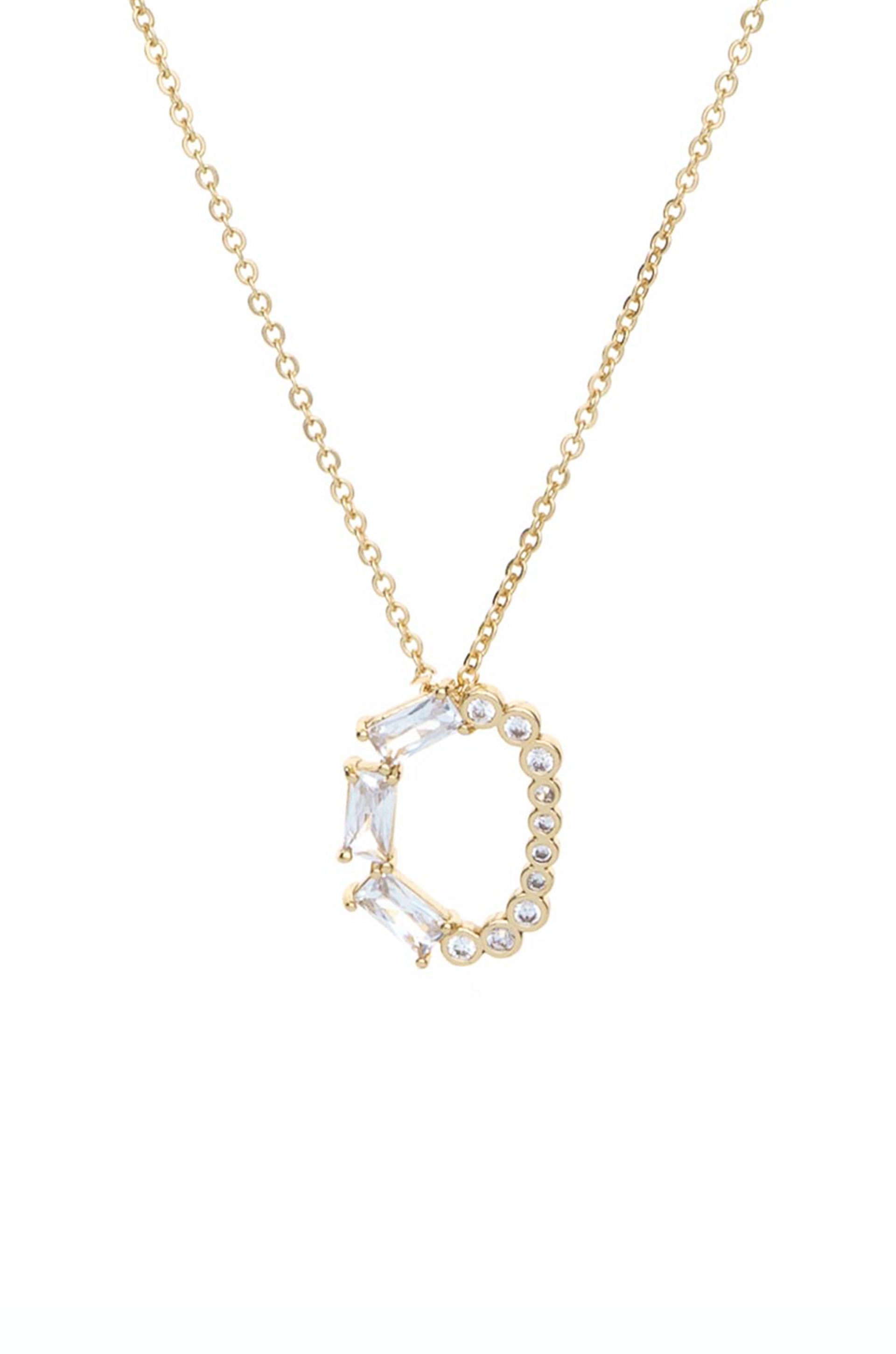 A gold necklace features a pendant shaped like the letter "C," adorned with clear gemstone accents, suspended against a plain white background, showcasing its elegant design.