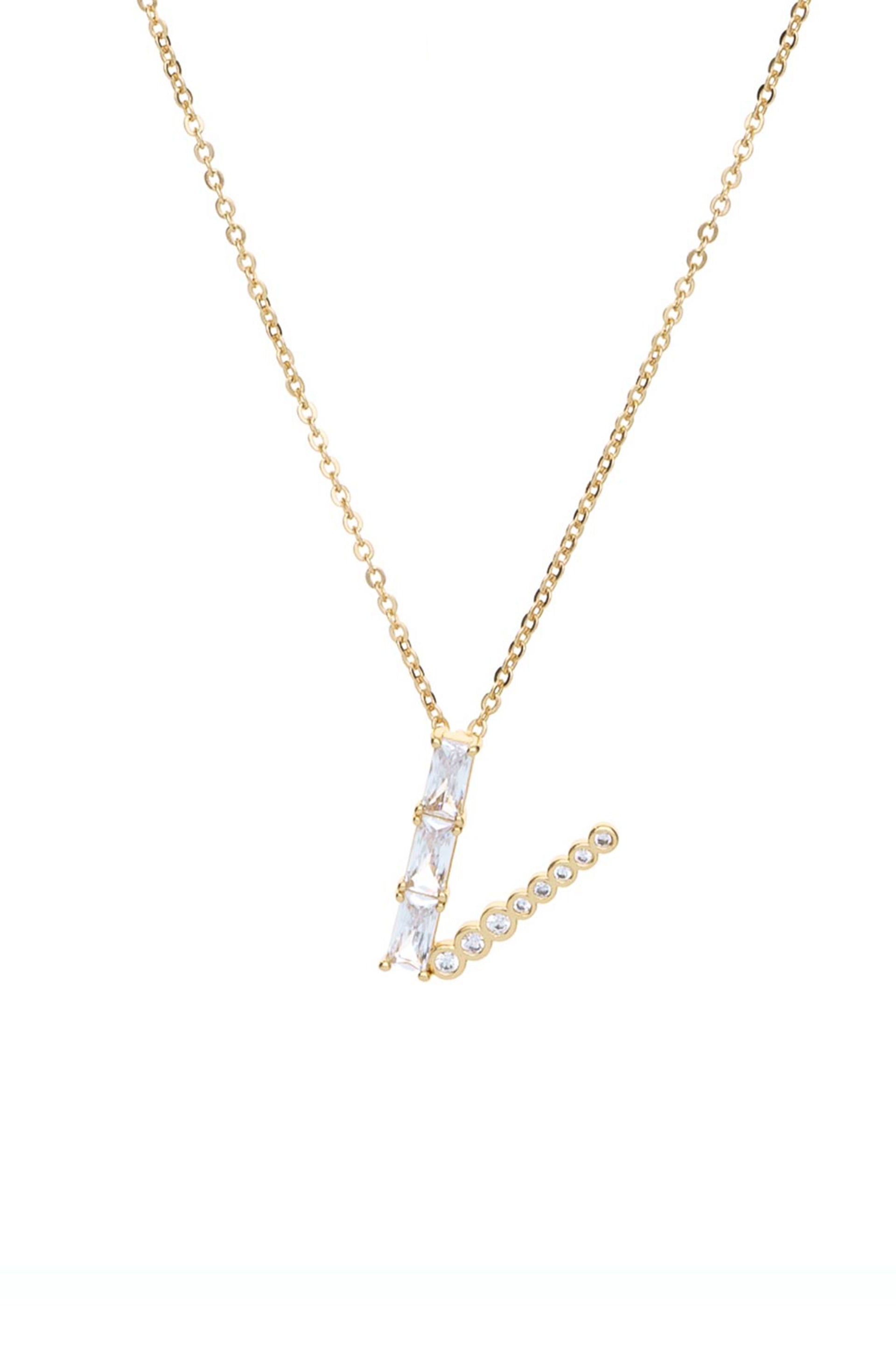 A gold chain necklace features a stylized letter 'L' crafted from clear gemstones. It hangs against a plain white background, emphasizing its elegance and design.