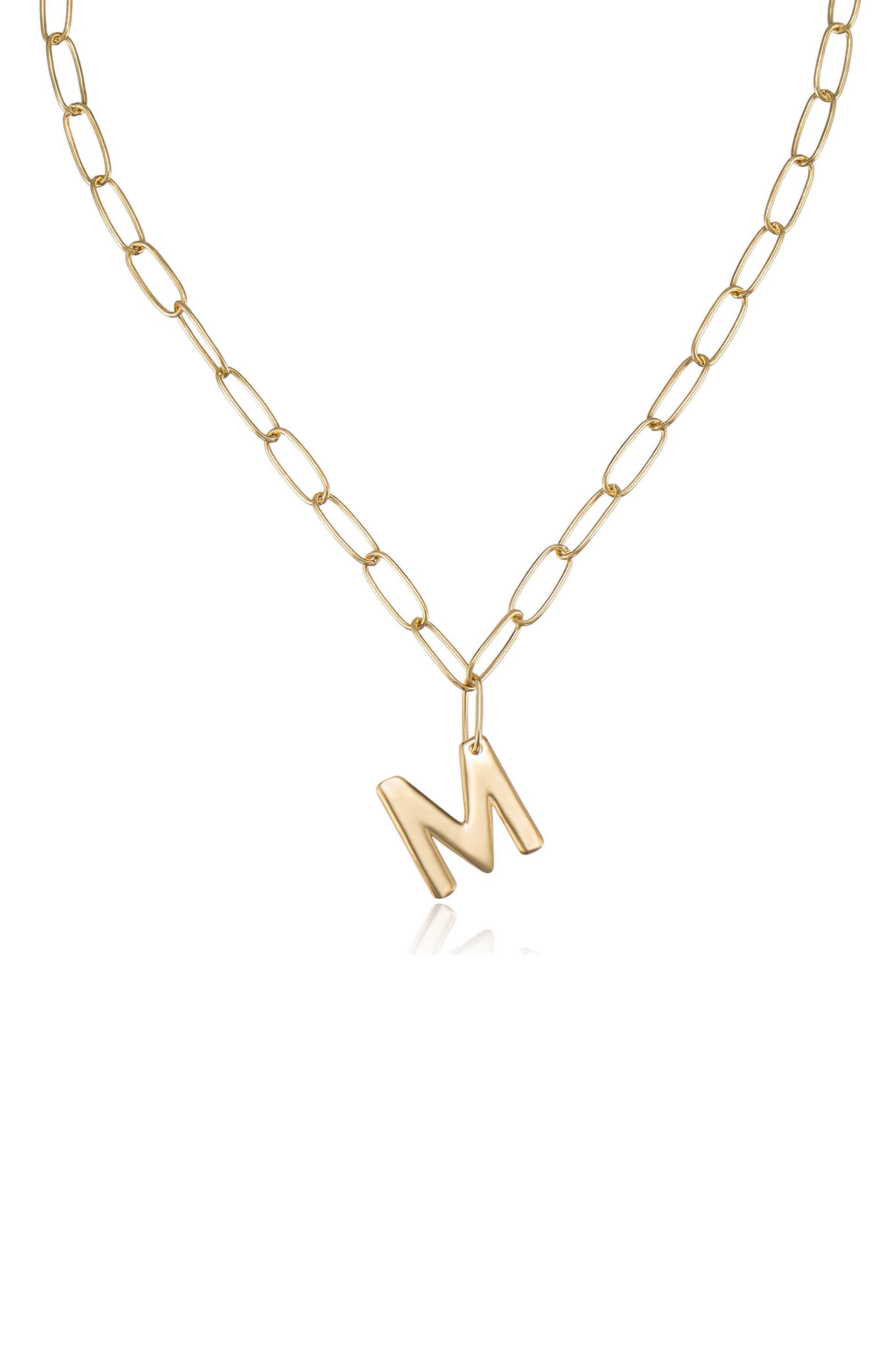 A gold chain necklace features an asymmetrical letter "M" pendant hanging from it. The necklace is set against a white background, emphasizing its shiny texture and design.