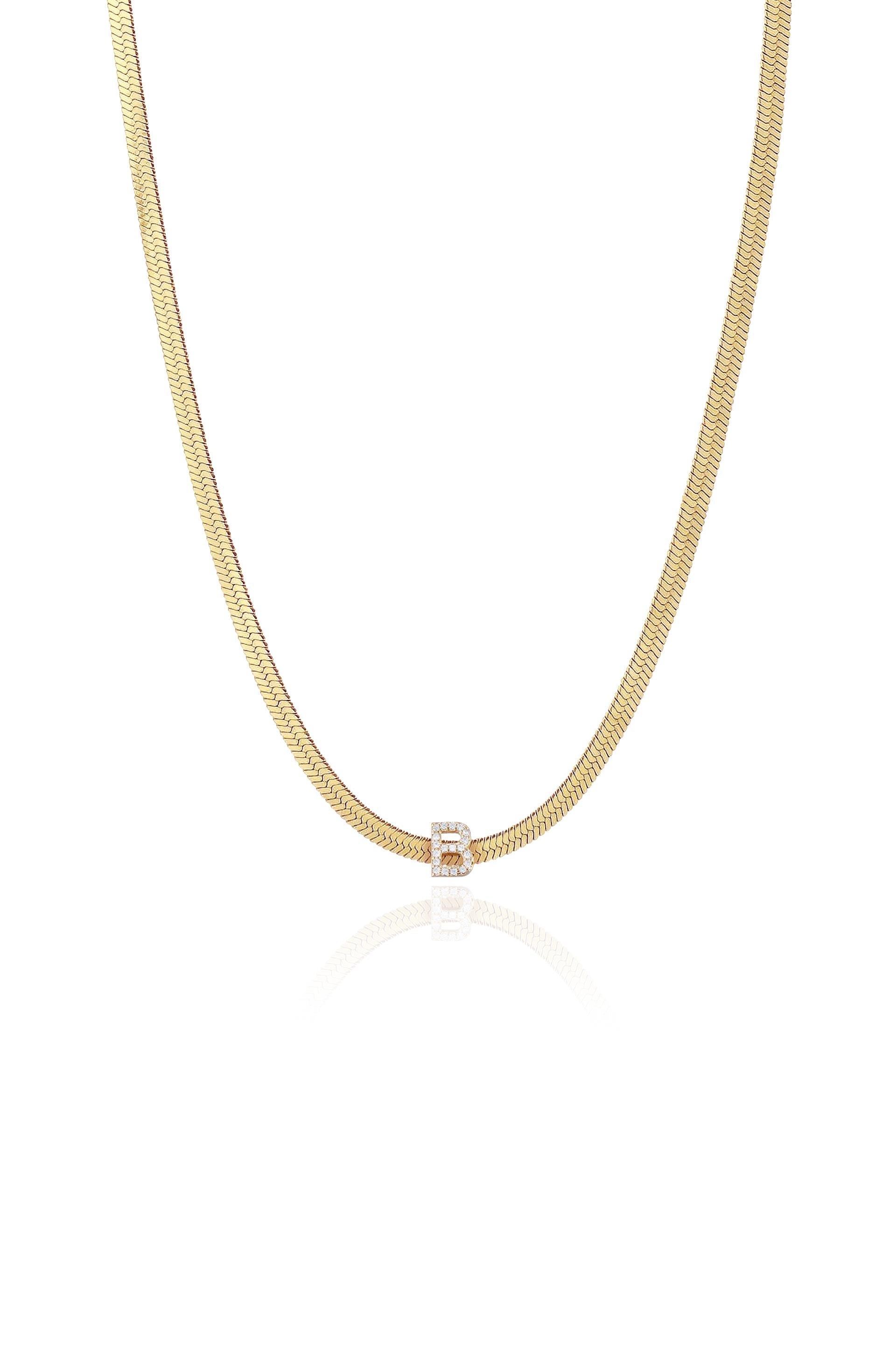 A gold chain necklace elegantly features a glimmering letter 'B' adorned with sparkling gemstones, reflecting light against a plain white background, emphasizing its luxurious design.