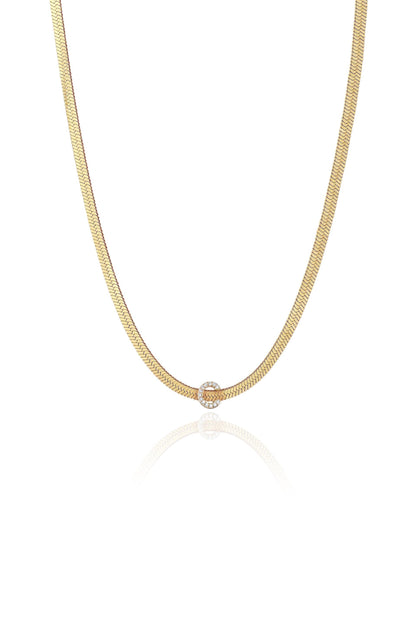 A gold chain necklace with a smooth, braided design features a circular diamond-encrusted clasp at the center, reflecting light on a neutral background.