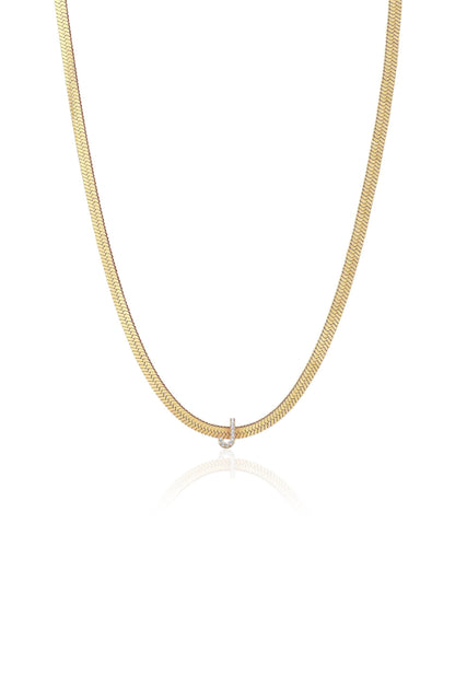 A gold chain necklace hangs gracefully, featuring a smooth, flat design with a small diamond-like pendant at the center, set against a simple white background, reflecting a soft shine.