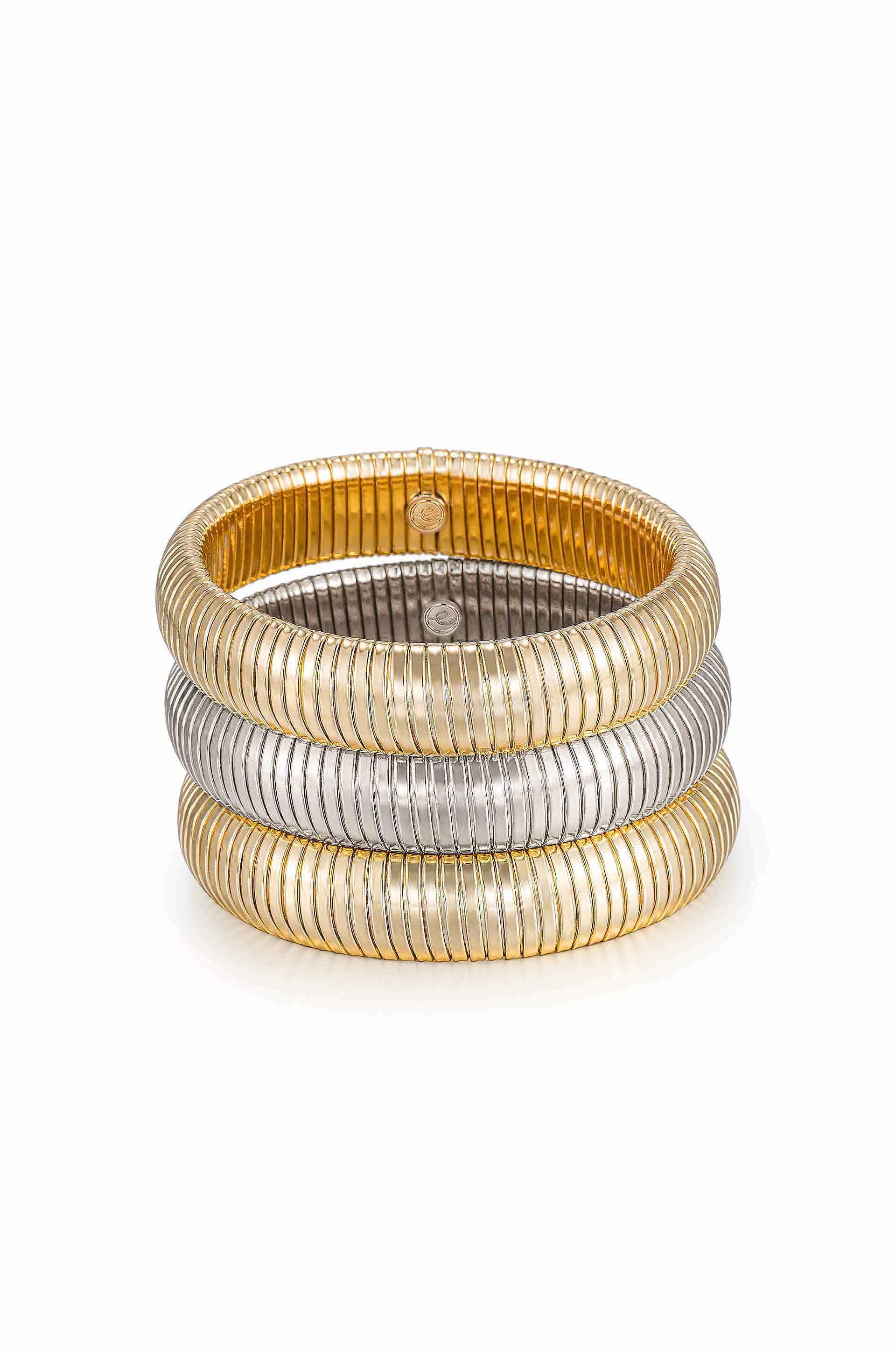 Three stacked elastic bracelets made of thin metal coils, featuring alternating shiny gold and silver colors, resting on a smooth, reflective surface. The design appears modern and stylish.