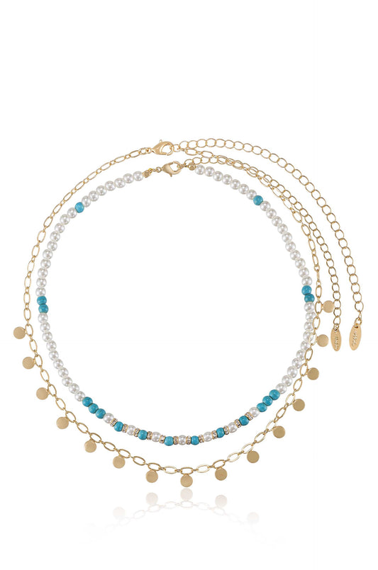 A delicate layered necklace features multiple strands of pearls, turquoise beads, and gold accents, elegantly arranged to create a stylish accessory suitable for various occasions.