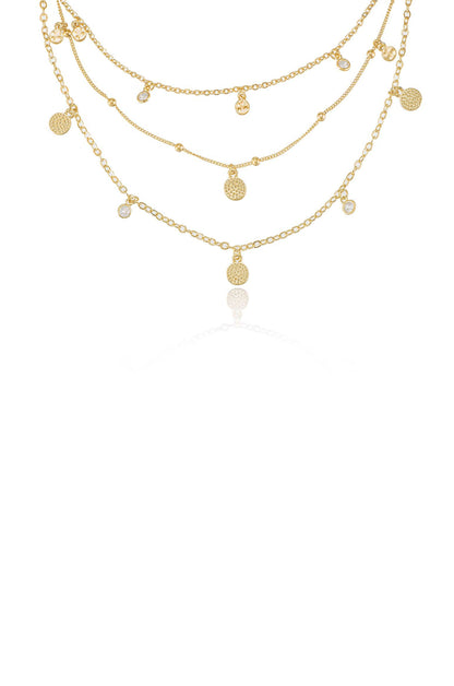 A layered gold necklace features multiple chains adorned with circular pendants and small gemstones, displayed against a clean, white background, emphasizing its elegant design and shine.