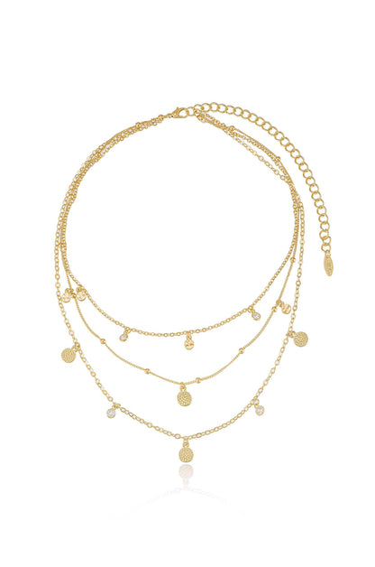 A three-tiered gold necklace featuring multiple delicate chains, adorned with small circular and sparkling charms. It appears elegant and ready for wear, set against a plain white background.