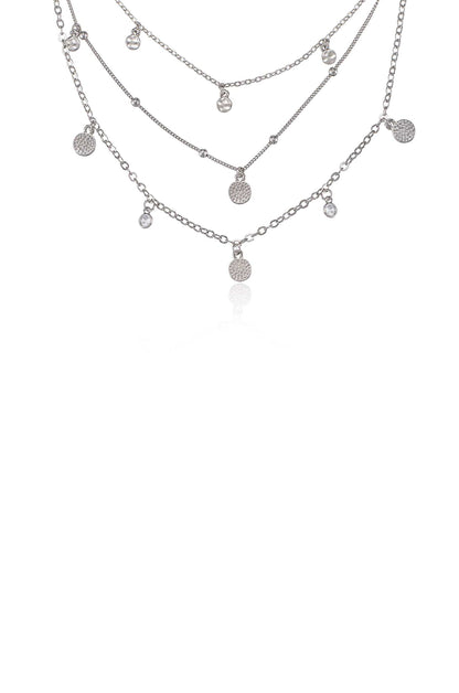 A silver necklace with multiple layered chains features various small pendants, including textured circles and clear beads, displayed against a white background.