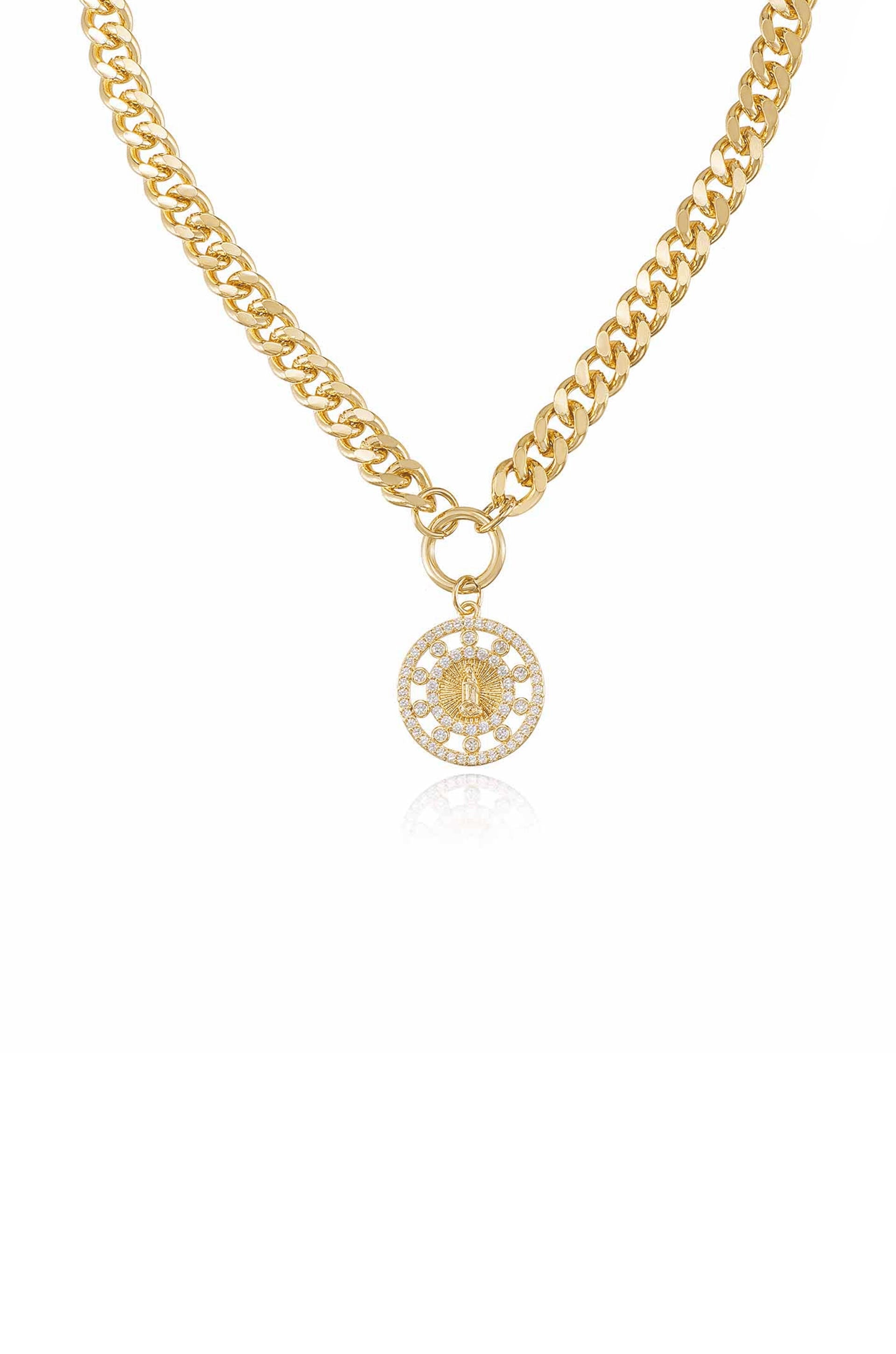 A gold chain necklace features a round pendant adorned with sparkling stones, showcasing an intricate design at its center, set against a plain white background.