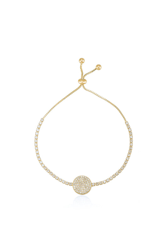 A delicate gold bracelet glimmers with tiny clear stones along a chain, featuring a circular centerpiece that is also adorned with sparkling gems, showcased against a plain white background.