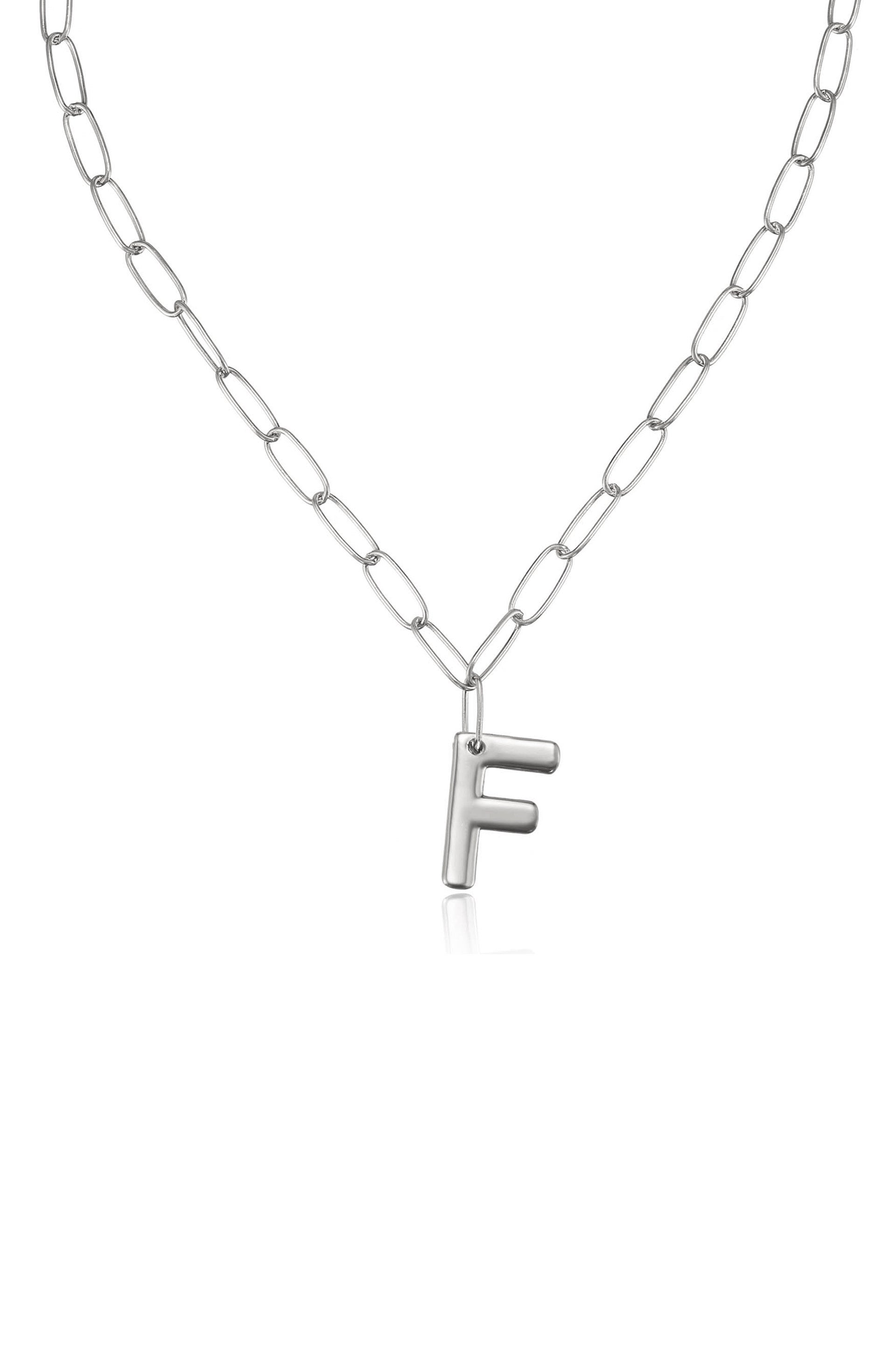 A silver chain necklace features an uppercase "F" pendant, hanging centrally. The background is plain white, emphasizing the simplicity and elegance of the piece.