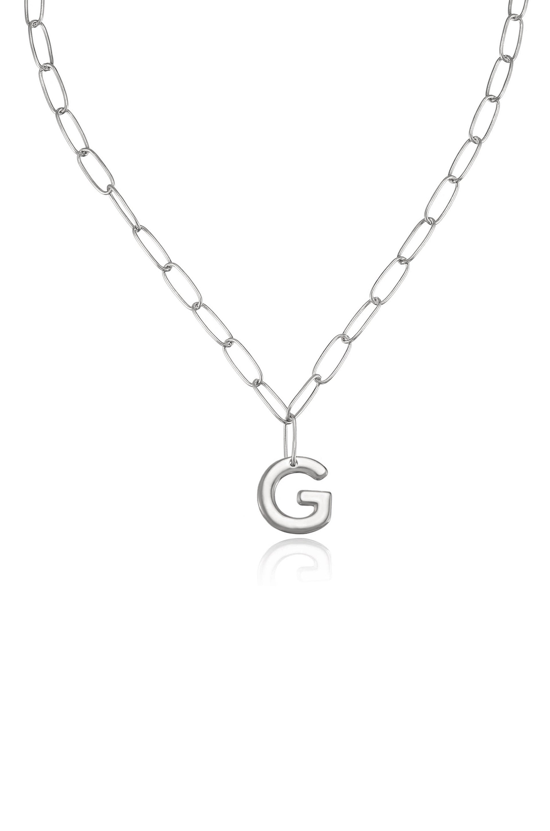 A silver chain necklace features an oversized letter "G" pendant at its center, suspended in a minimalist style against a plain white background, emphasizing its simple elegance.