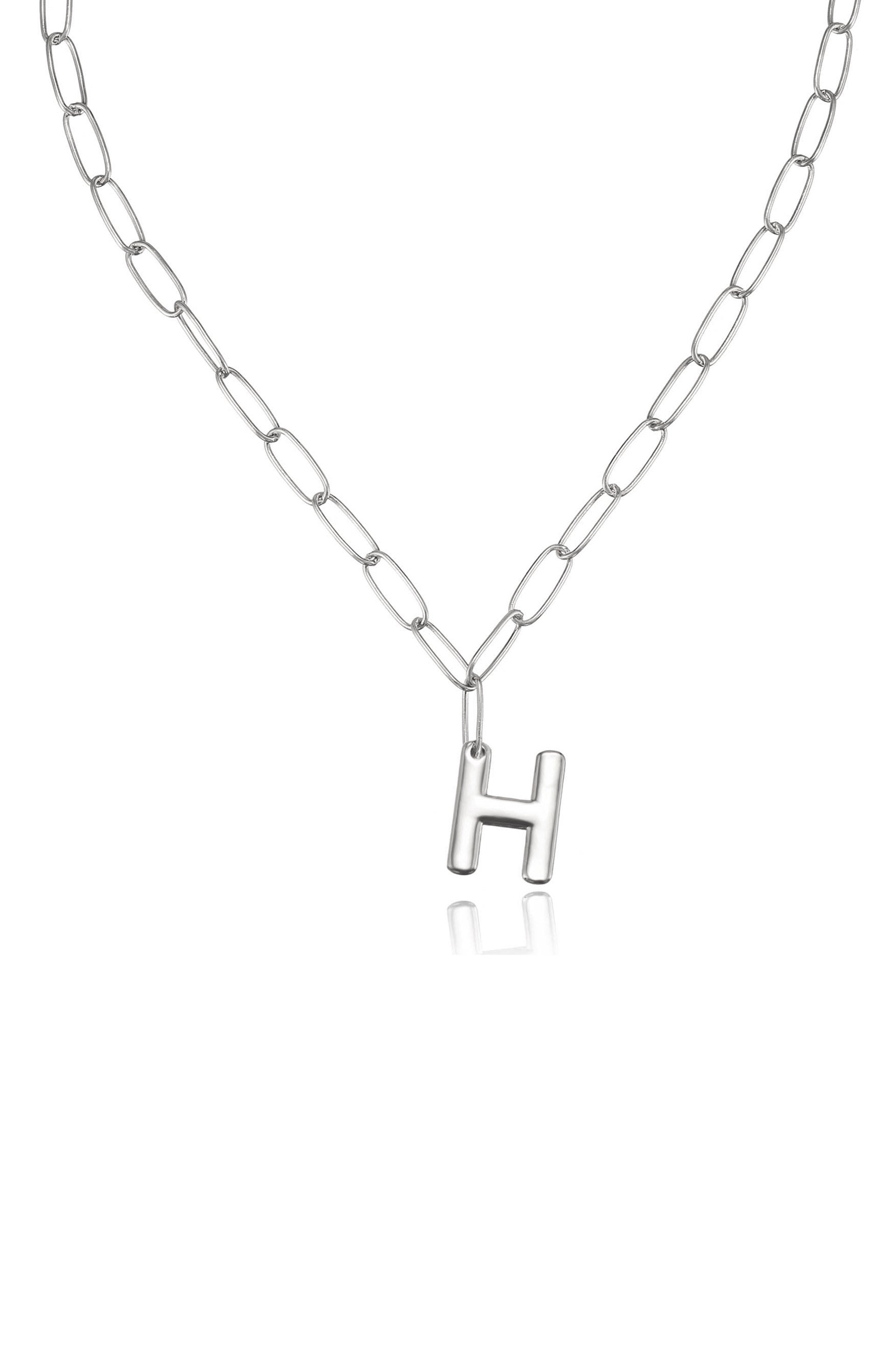 A silver chain necklace features an uppercase "H" pendant. The necklace hangs against a plain background, emphasizing its simple yet elegant design.