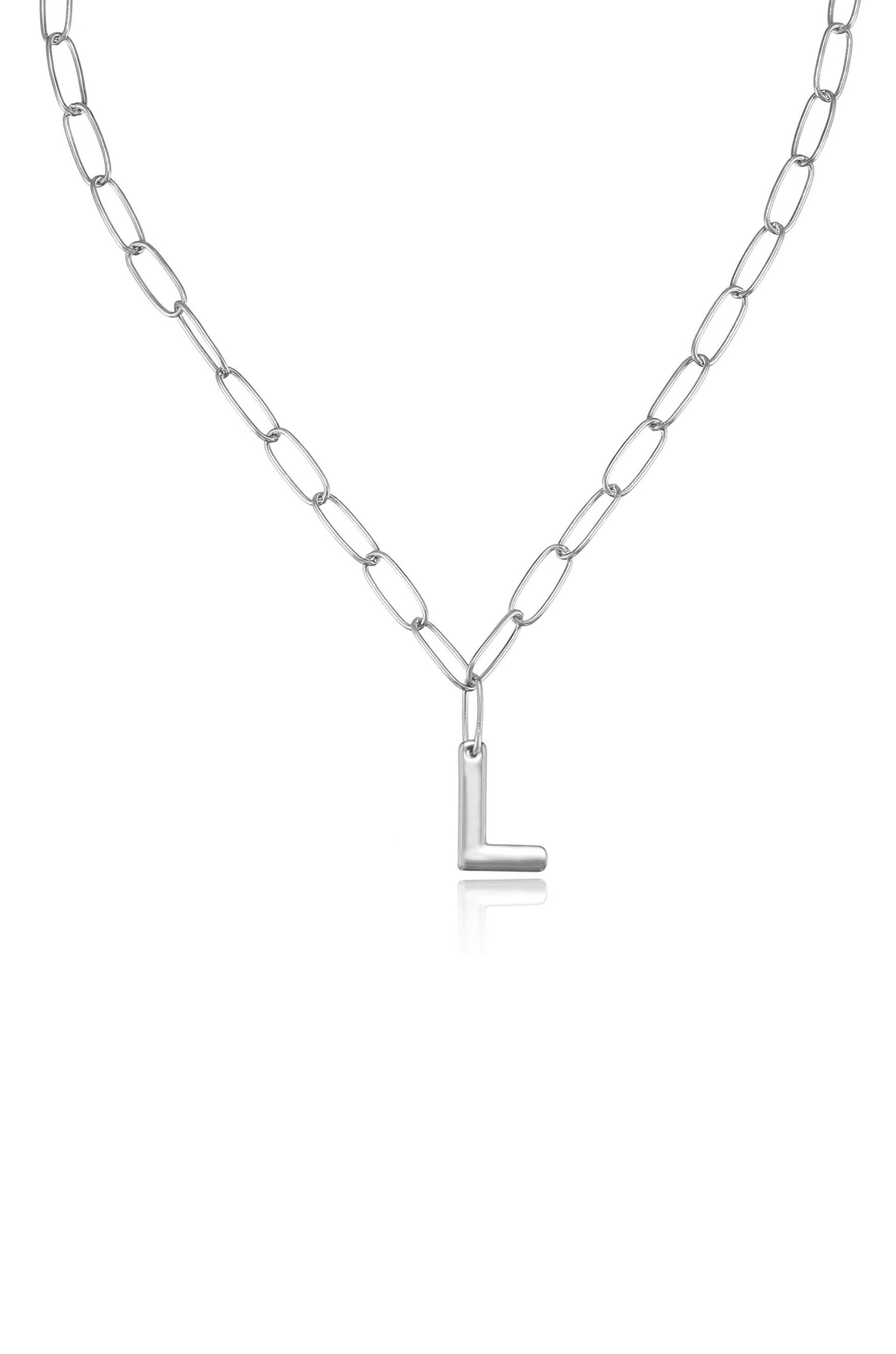 A silver chain necklace features an oversized, stylized letter "L" pendant hanging prominently. The necklace is displayed against a plain white background, emphasizing its sleek and modern design.