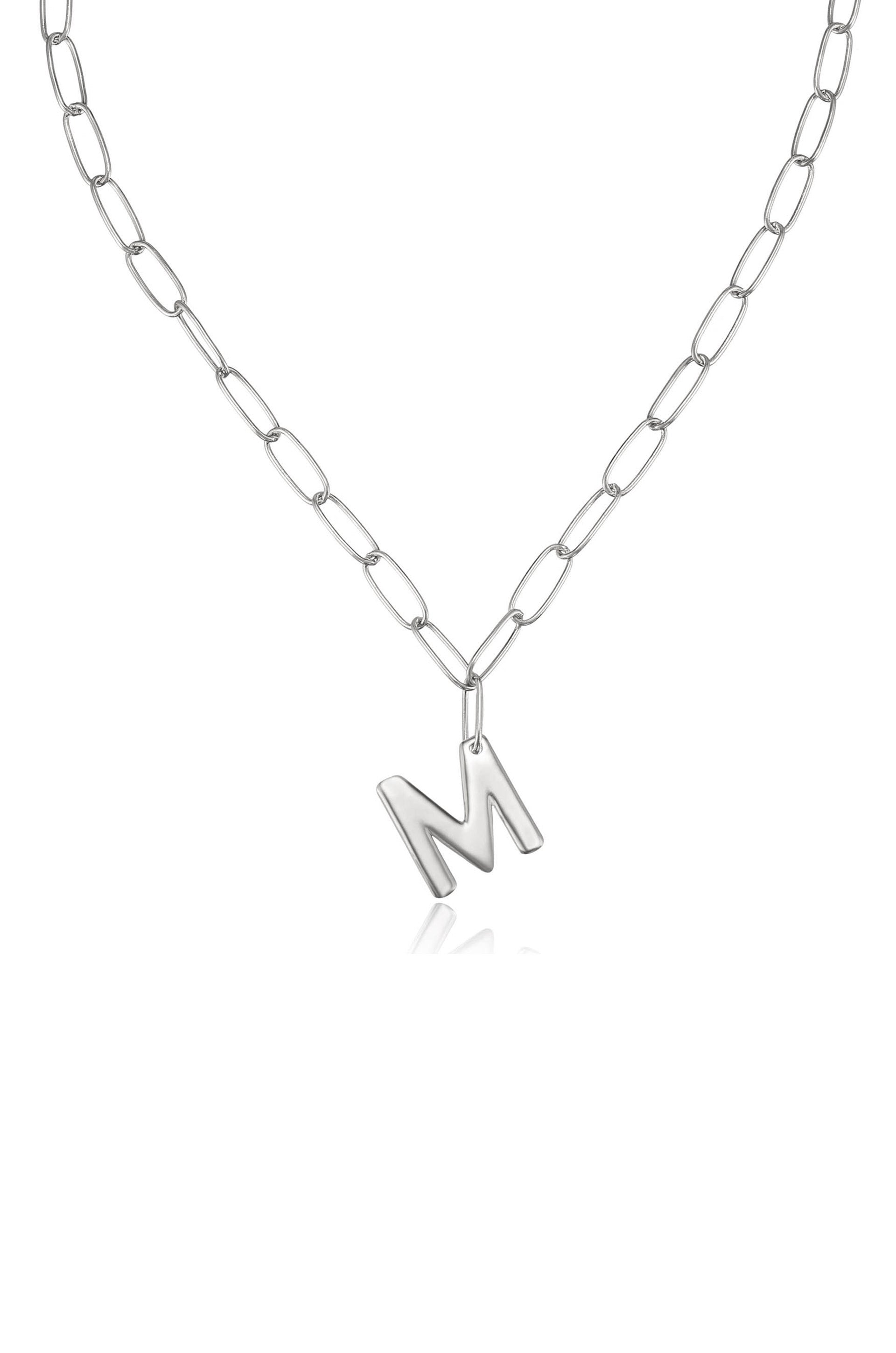 A silver chain necklace features a prominent letter "M" pendant, hanging centrally against a white background, emphasizing its contemporary design and personal touch.