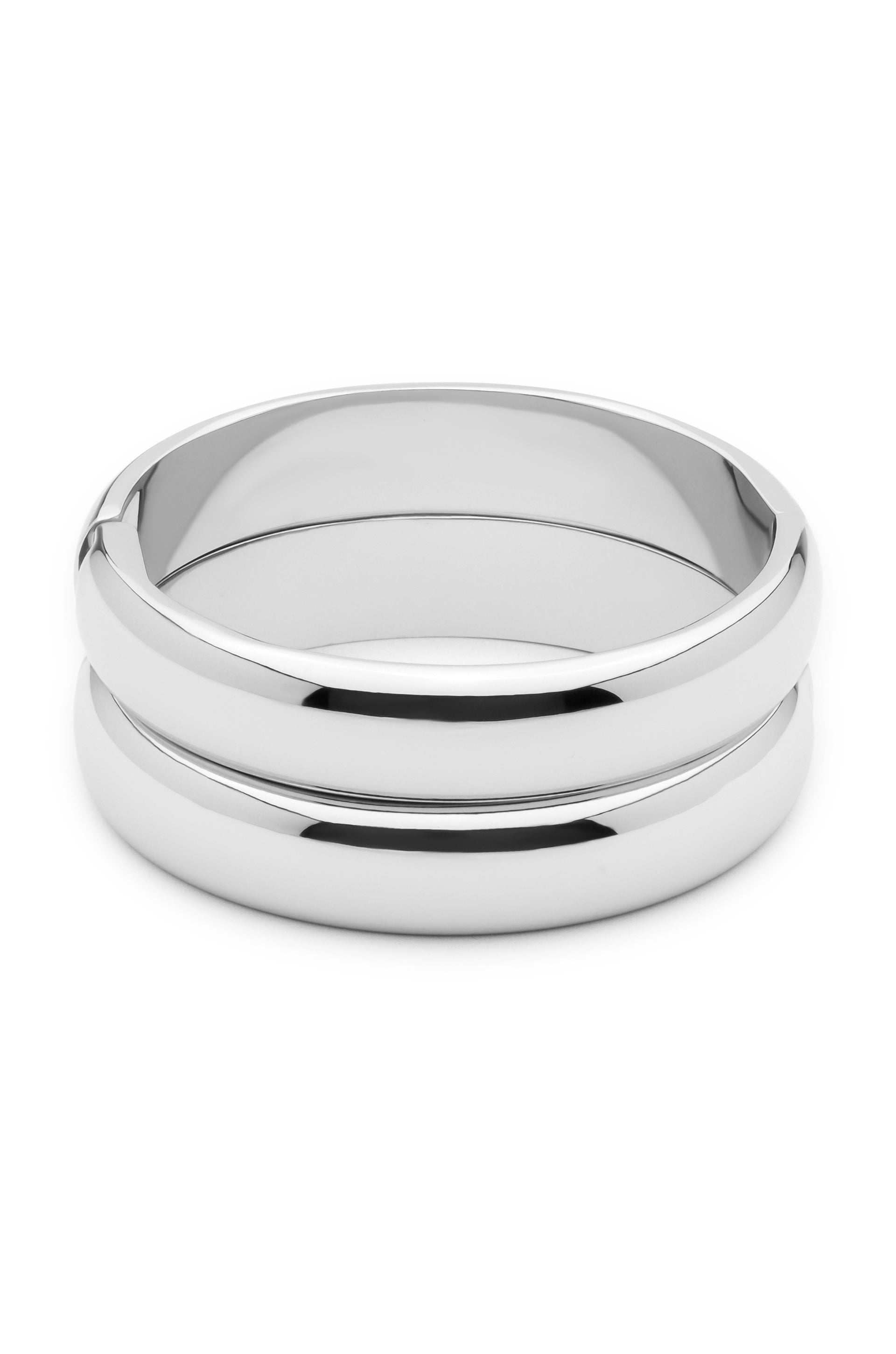 A pair of polished silver rings sits side by side, reflecting light. The circular objects are smooth and glossy, suggesting a stylish and elegant design suitable for jewelry.