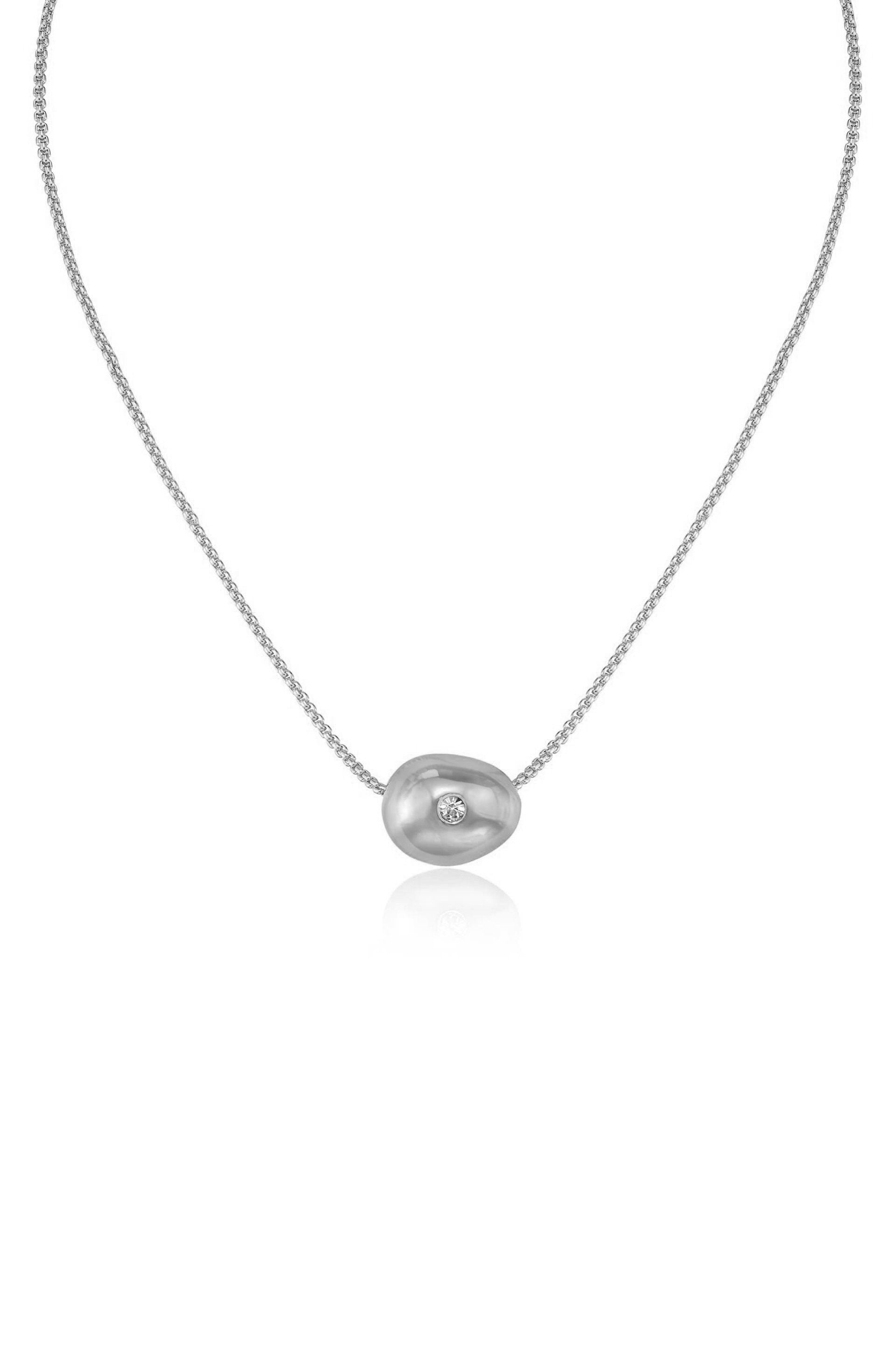 A silver necklace features a polished, bean-shaped pendant with a small diamond embedded in its center, resting against a white background, showcasing its elegant design.