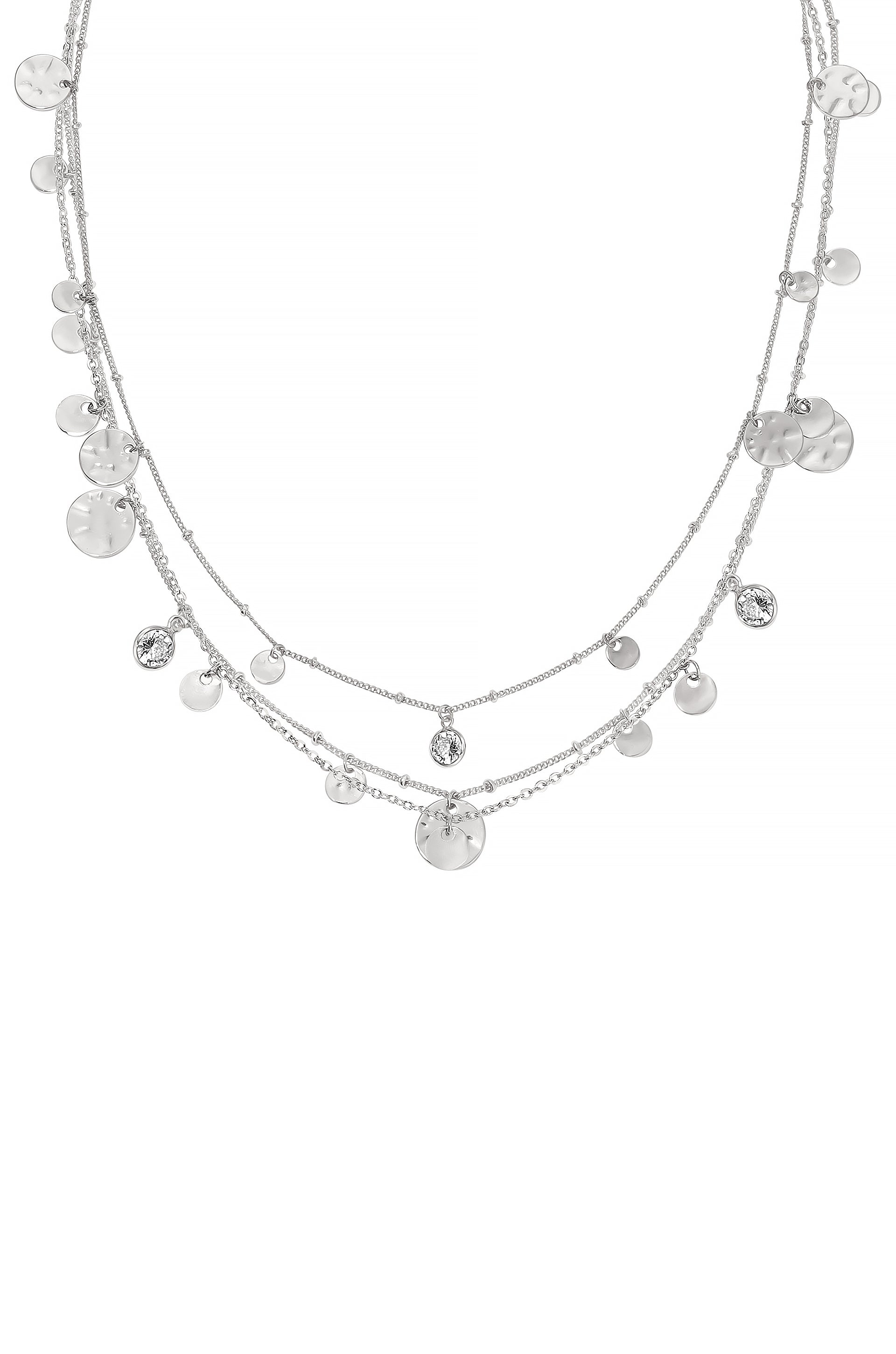 A layered silver necklace features multiple chains adorned with shiny circular and faceted pendants, elegantly displayed against a neutral background, illustrating a delicate and sophisticated jewelry design.