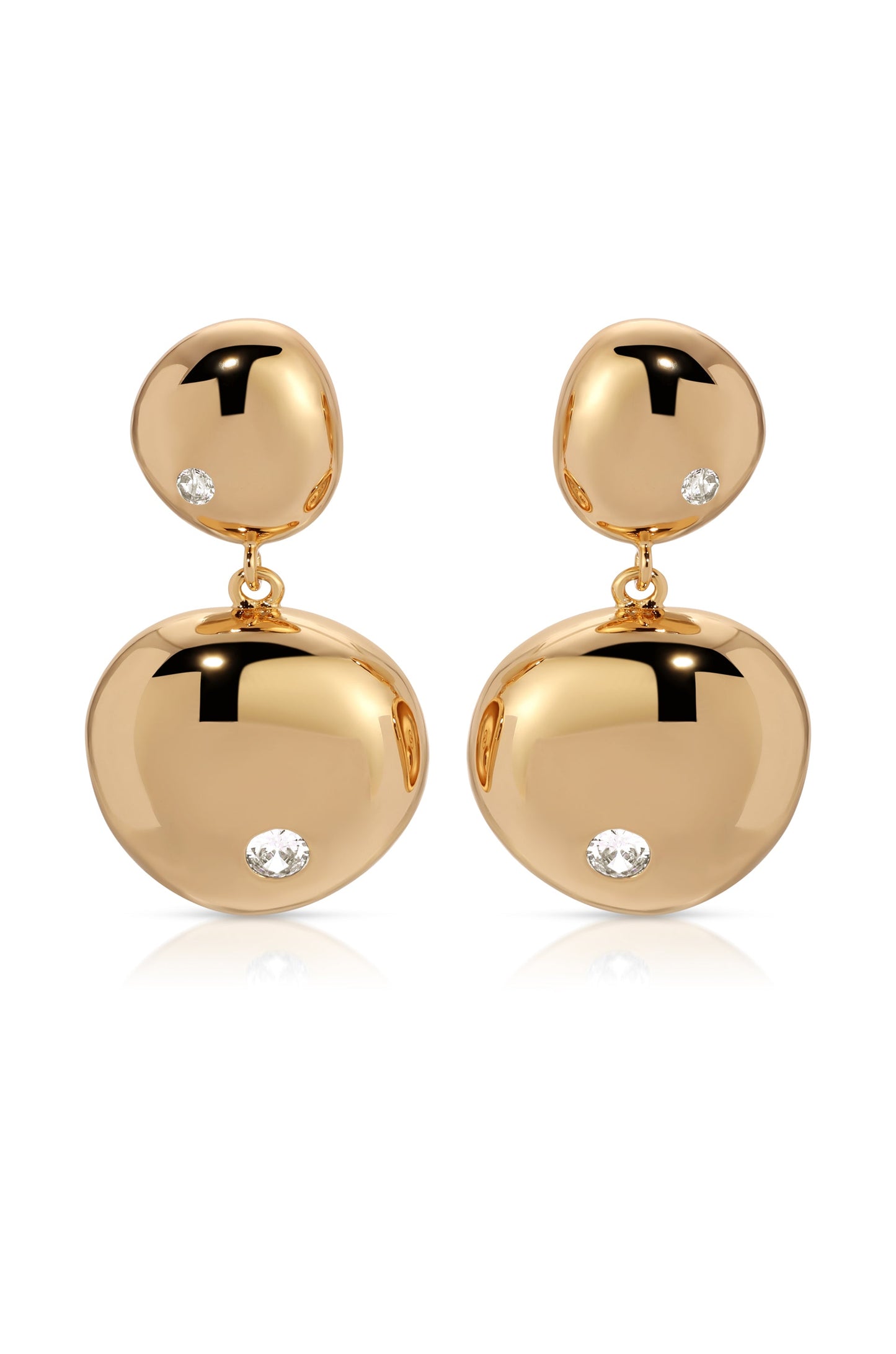 Two gold earrings dangle elegantly, featuring polished, rounded shapes adorned with small, sparkling diamonds. They rest on a white surface, reflecting light and enhancing their luxurious appearance.