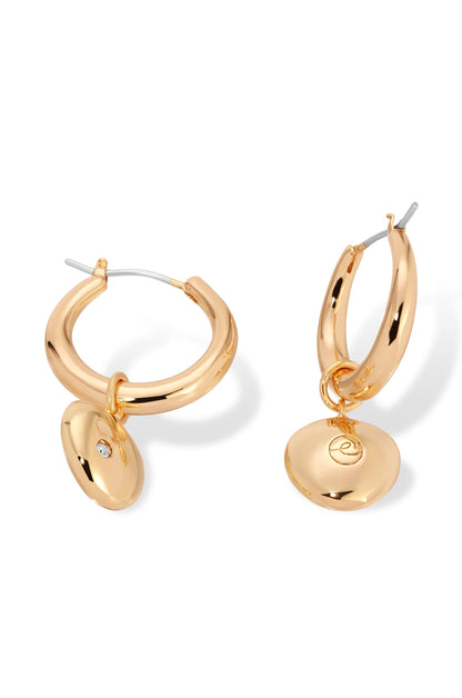 Gold hoop earrings are showcased, featuring a polished surface and a dangling circular charm. They are presented against a plain white background, emphasizing their shiny and elegant design.