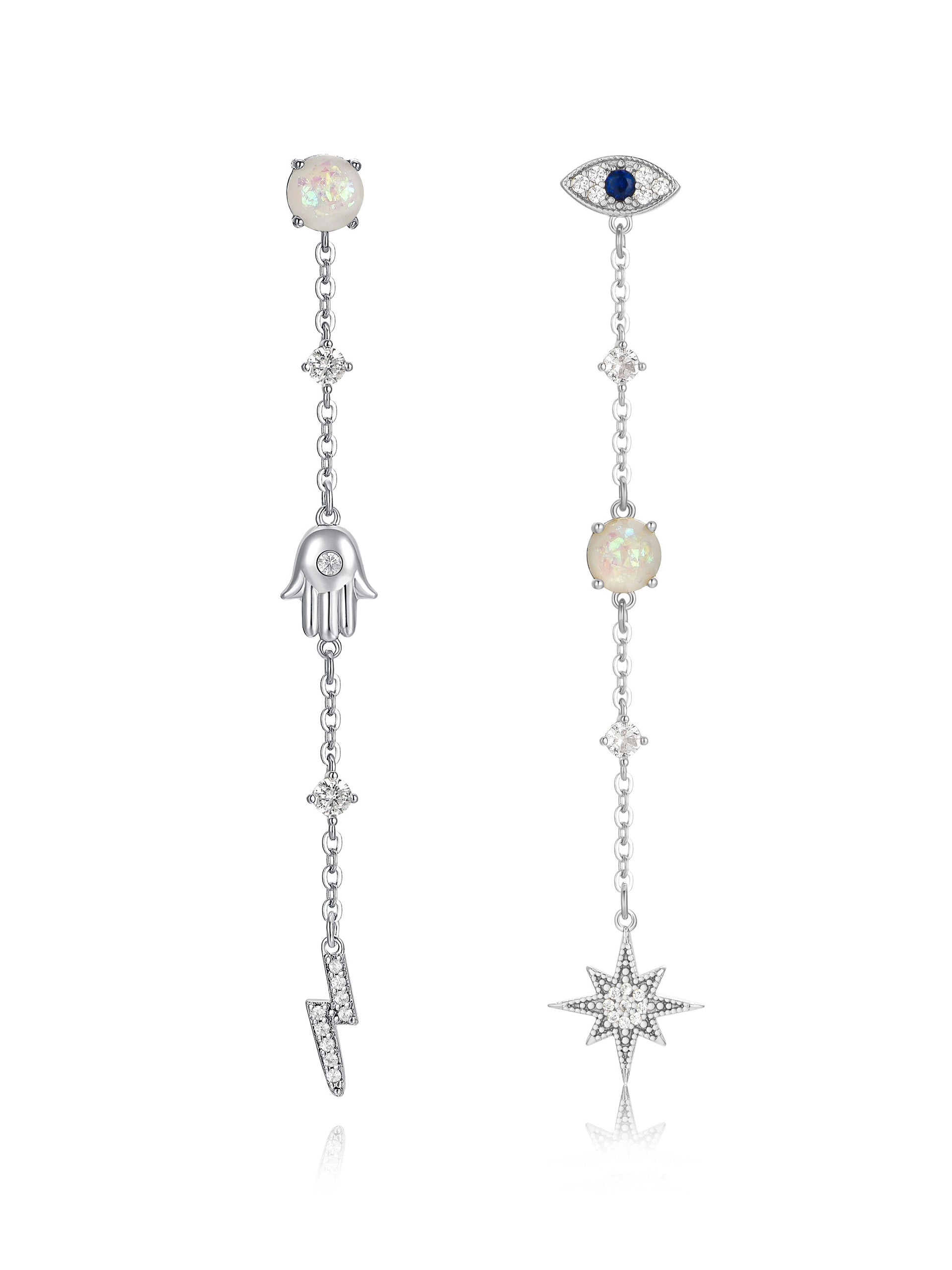 Two silver earrings hang vertically, featuring opal-like stones and decorative symbols: a hand, an eye, a lightning bolt, and a star, set against a neutral background.