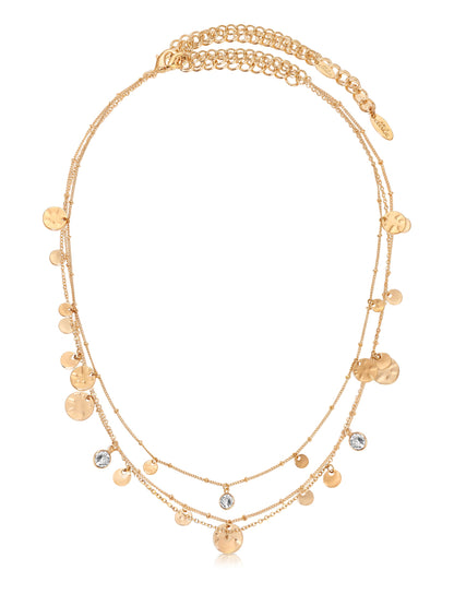 A gold necklace features multiple delicate chains adorned with circular pendants and a few sparkling stones. It hangs gracefully, reflecting light, suitable for formal or casual wear.