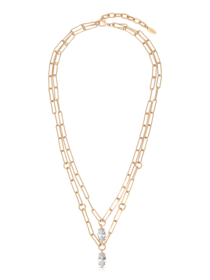 A gold chain necklace features two intertwined strands, adorned with elongated links and two marquise-cut clear stones suspended at the center, set against a plain background.