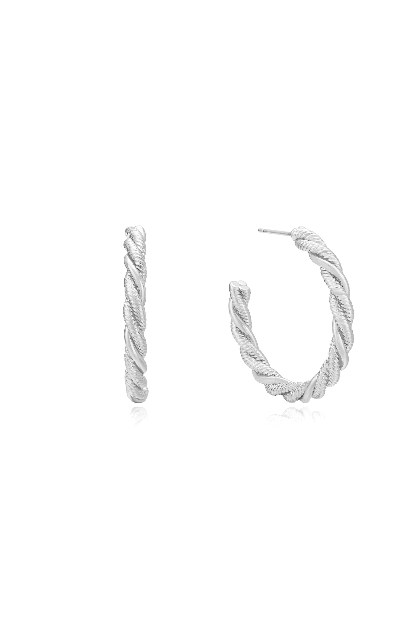 Two silver hoop earrings are displayed, one upright and one angled, showcasing a twisted design. They rest on a reflective surface against a plain white background.