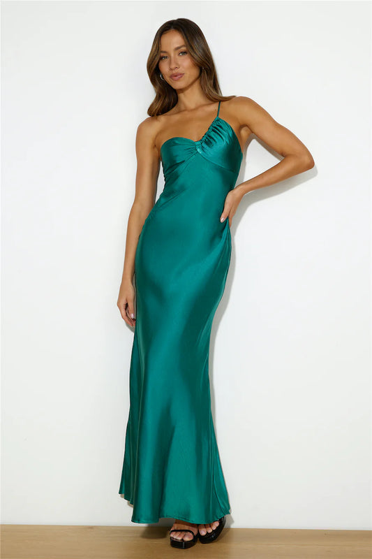 A woman is posing confidently in a vibrant green satin gown with a fitted bodice and flowing skirt, showcasing a modern and elegant style against a plain white background.