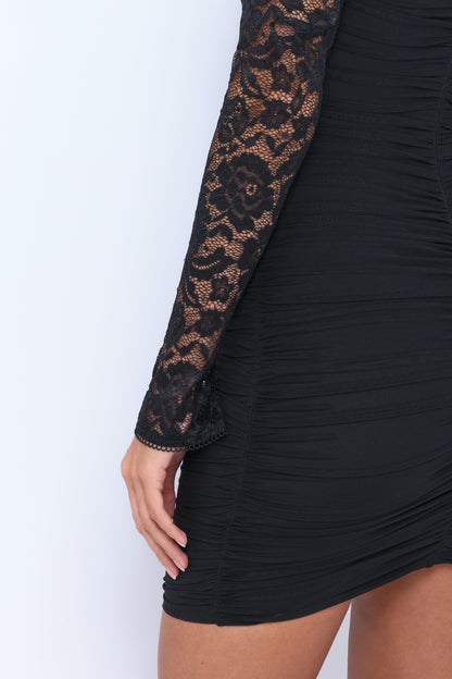 A close-up of a woman's arm in a black lace sleeve dress. The fabric features ruching and floral patterns, set against a plain light background. The hand rests casually on the waist.