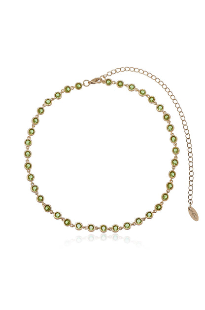 A delicate gold necklace adorned with green stones is displayed against a white background. It features a chain for length adjustment and a small tag at one end.